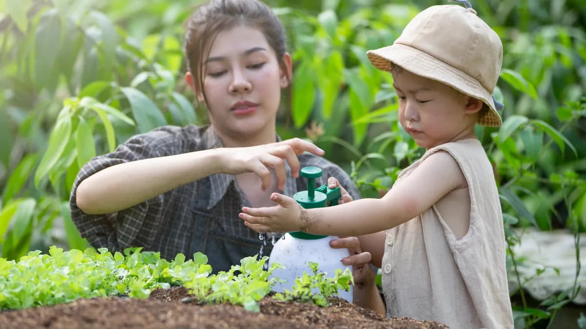 Mother teaching children to water seedlings in a garden