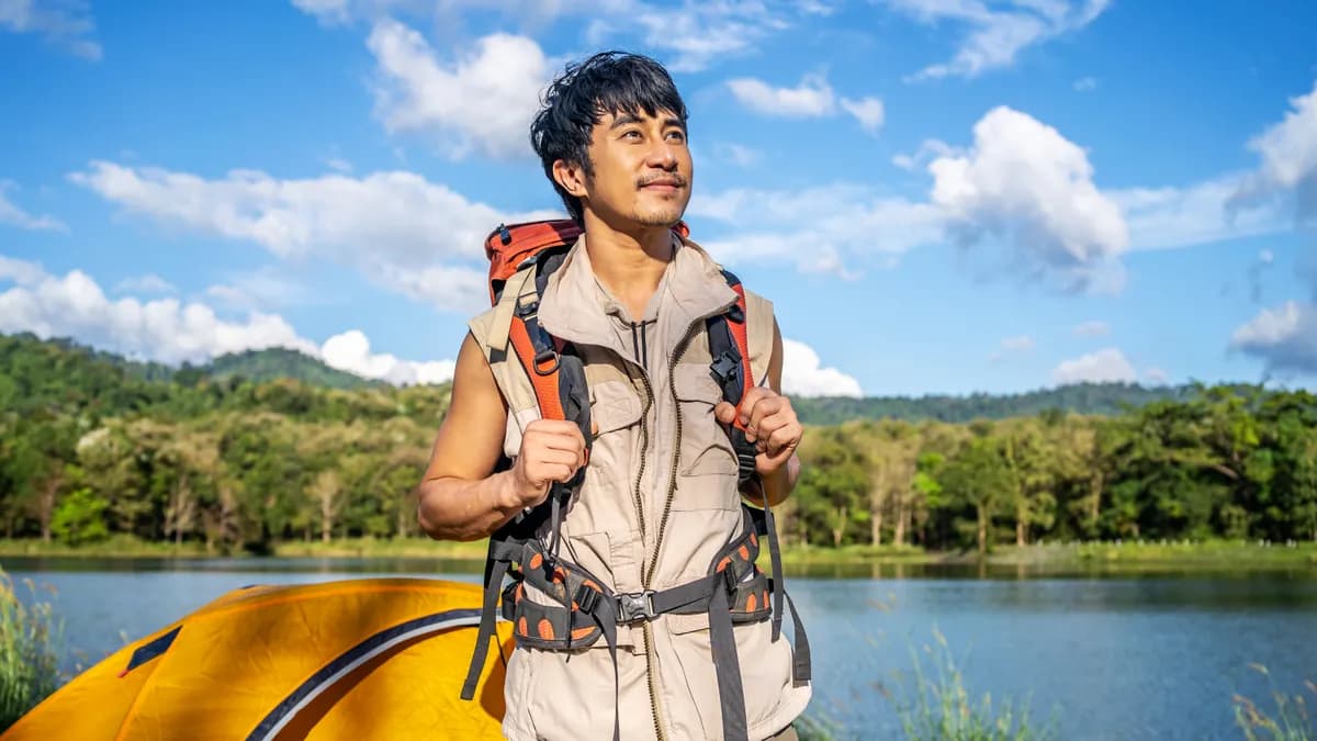 Male traveler setting up camp near his tent in the wilderness